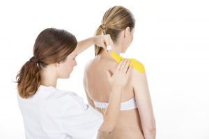 Physiotherapist applying tapes on a shoulder